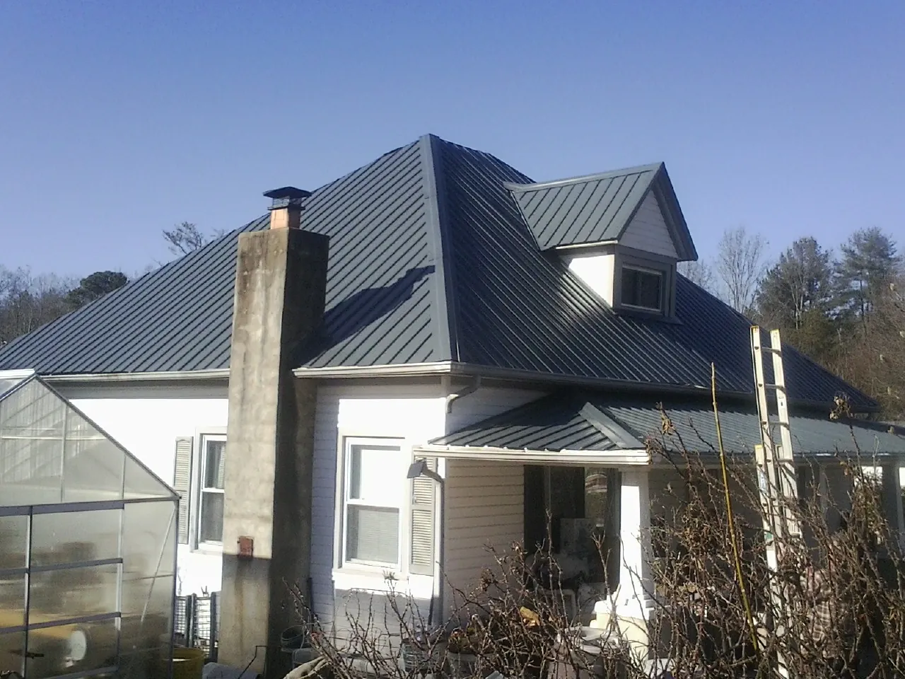 Dark blue standing seam metal roof on a white farmhouse with dormer — Slate & Tile Roof Repair by Roofing Brothers in Washoe Valley