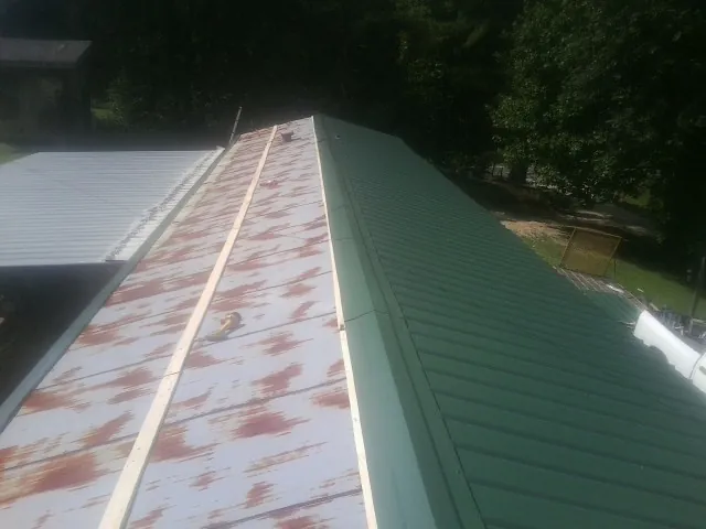 Old rusted panels beside newly installed green metal roofing — Wind Damage Roof Repair by Roofing Brothers in Washoe Valley