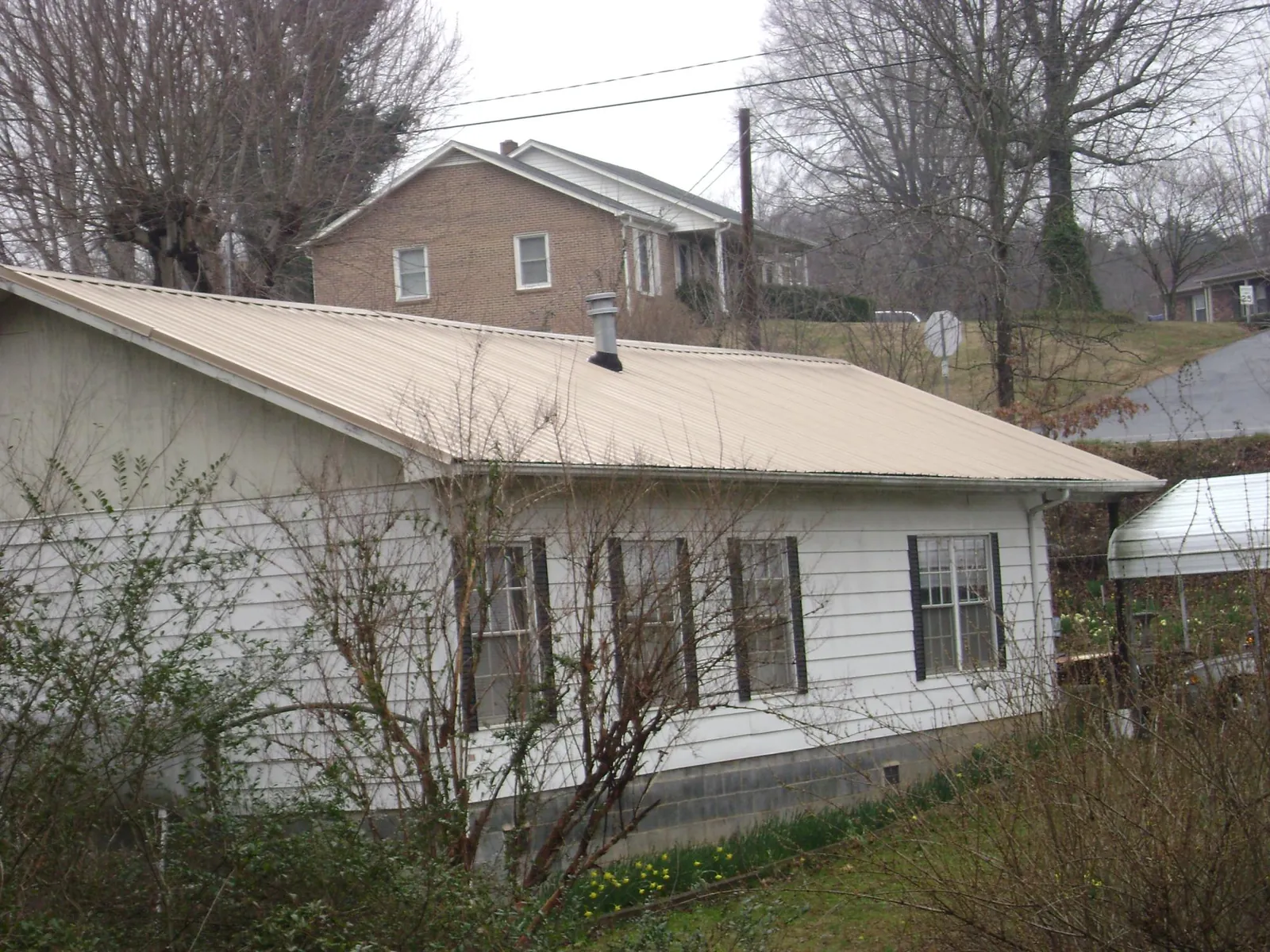 Tan metal roof on a white sided house set into a hillside — Commercial Roofing by Roofing Brothers in Washoe Valley