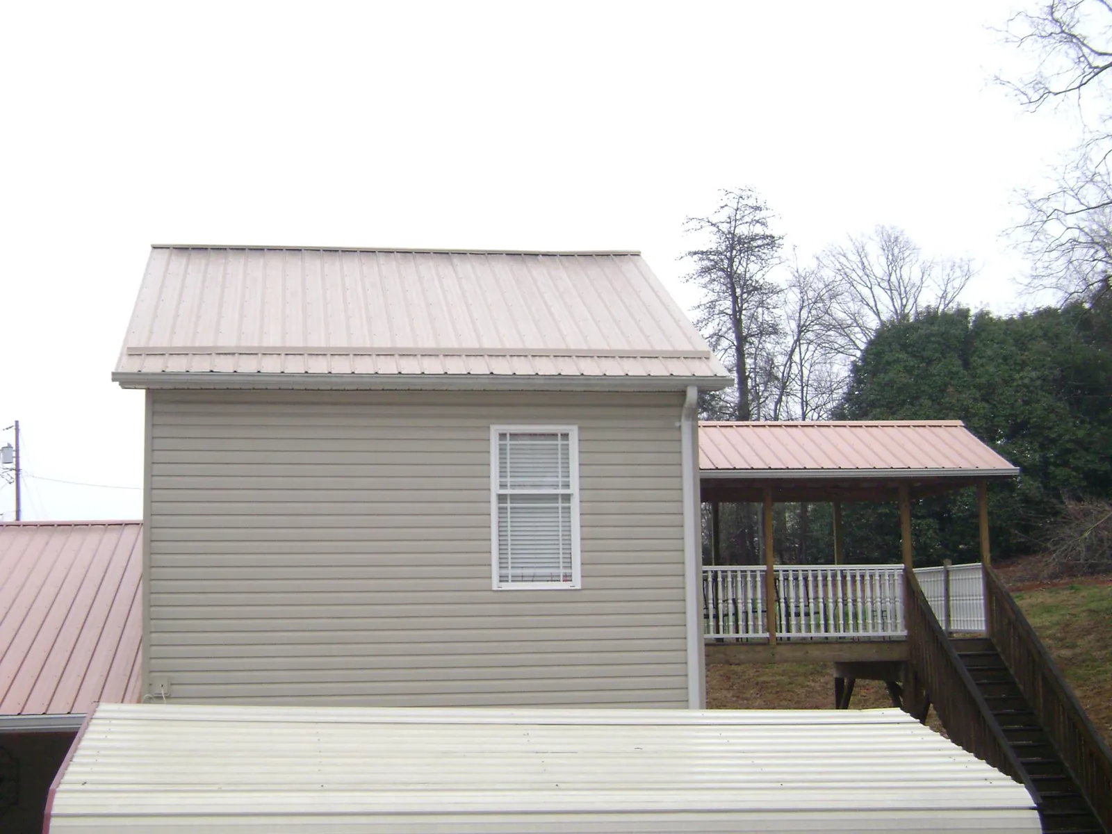 Tan metal roofs on a two story addition and attached porch, from a Roof Replacement job in Washoe Valley