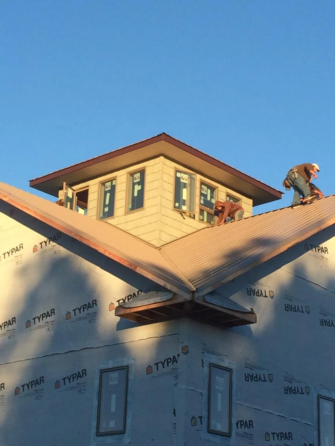 Roofers working around a rooftop cupola on a new metal roof at sunset — Roof Waterproofing in Washoe Valley by Roofing Brothers